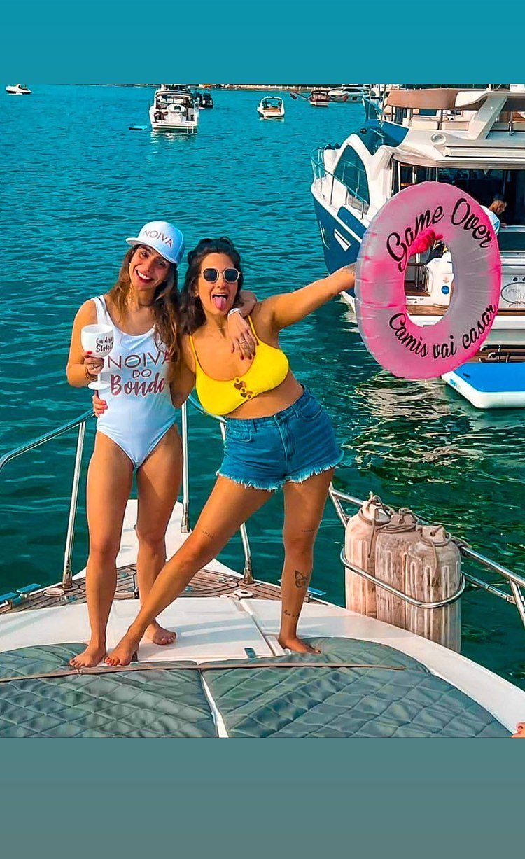 Duas amigas na proa, água turquesa ao fundo